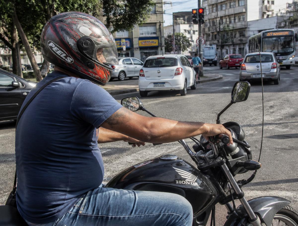 Motociclista parado no semáforo em via urbana